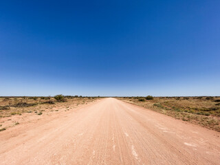 Fototapeta na wymiar Outback desert dirt road with blue sky, Northern Territory, Australia.