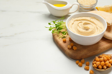 Delicious hummus and different ingredients on white marble table. Space for text