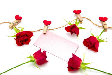 Greeting blank card and red rose flowers hanging on a rope on clothespins with hearts. Love. Copy space.	