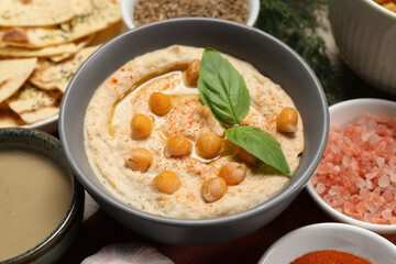 Delicious creamy hummus with chickpeas and different ingredients, closeup