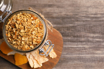 Jar of dried orange zest seasoning and fresh peel on wooden table, flat lay. Space for text