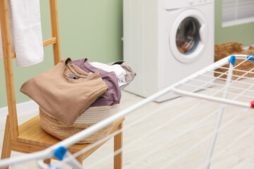 Fototapeta na wymiar Laundry basket filled with clothes on chair in bathroom. Space for text