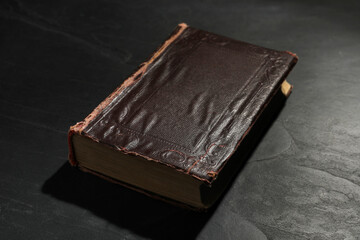 One old hardcover book on black textured table