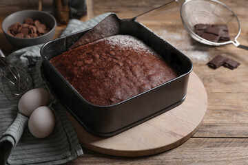 Homemade chocolate sponge cake and ingredients on wooden table
