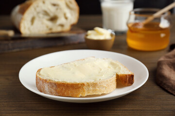 Sandwich with butter near honey on wooden table, closeup