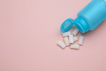 Jar with chewing gums on light pink background, flat lay. Space for text