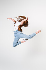 A teenage girl in jeans and a white T-shirt performs dance moves. White background