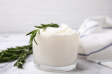 Delicious pork lard with rosemary in glass on white marble table, closeup