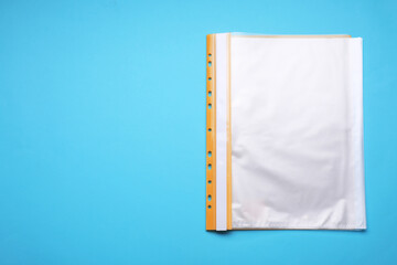 File folder with punched pockets on light blue background, top view. Space for text