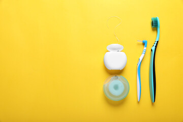 Flat lay composition with dental floss and different teeth care products on yellow background. Space for text