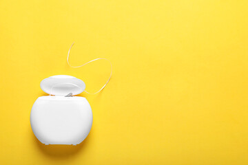 Container with dental floss on yellow background, top view. Space for text