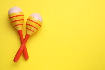 Colorful maracas on yellow background, flat lay with space for text. Musical instrument