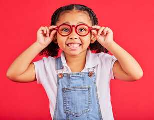 Excited child, portrait or fashion glasses on red background in children trend, eyes care or wellness health. Smile, happy or little girl with optometry frames for vision support or medical insurance