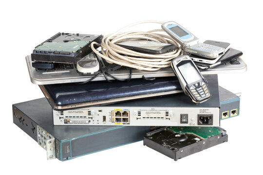 Stack Of Old And Obsolete Computer, Networking Devices Isolated On White Background. Switch, Router, Laptop, Cables And Old Mobile Phones