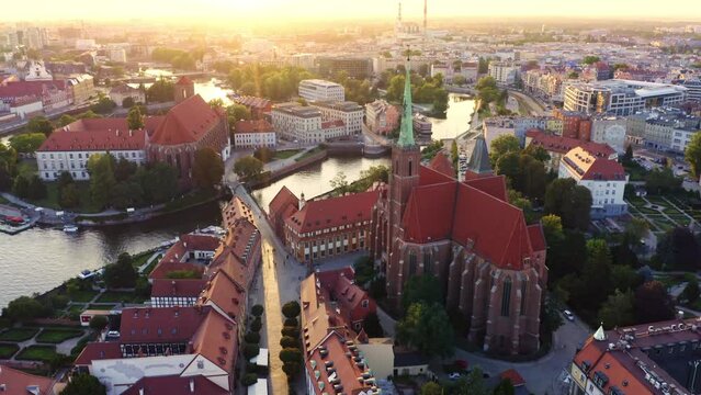 4k aerial footage under Church of Roman Catholic parish of St.Holy Cross near river Oder in Wroclaw, Poland. Nice calm view at old town in golden sunset rays of light. Europe, summer, weekend.