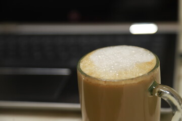 a cup of milk coffee with hot foam on top