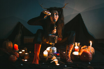 Close up woman witch with horns making soup more flavorful portrait picture. Closeup front view...