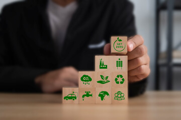 Businessman puting wooden cubes with green net zero icon on table. Net zero and carbon neutral concept. Net zero greenhouse gas emissions target. Climate neutral long term strategy.