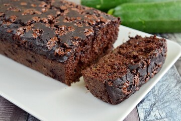 Zucchini chocolate cake. Moist double chocolate cake with grated zucchini, cocoa powder, chocolate and chocolate chips. Shot on wooden background