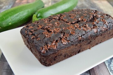 Zucchini chocolate cake. Moist double chocolate cake with grated zucchini, cocoa powder, chocolate and chocolate chips. Shot on wooden background