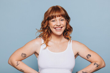 Portrait of a happy young woman with tattoos standing in a studio