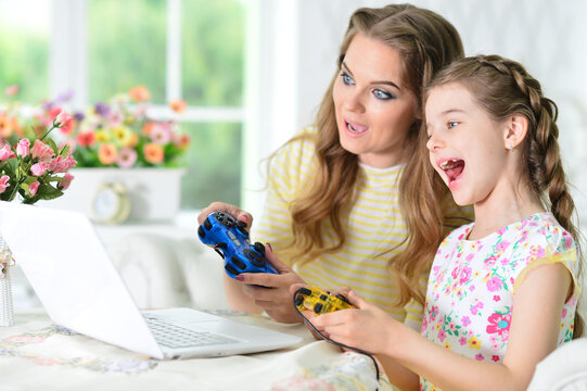 mother and daughter using laptop playing game
