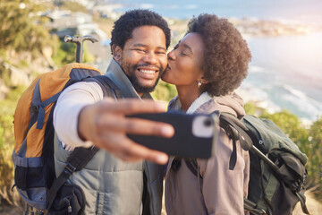 Selfie, kiss and black couple hiking on mountain for fitness, fun and romantic walk in natural landscape. Romance, man and woman taking self portrait in nature with smile in mountains on island trip