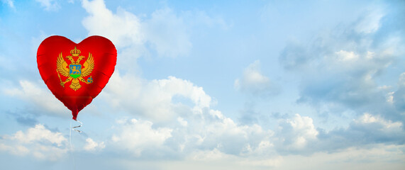 Flag of Montenegro on heart-shaped balloon against sky clouds background. Education, charity, emigration, travel and learning. Montenegro language concept