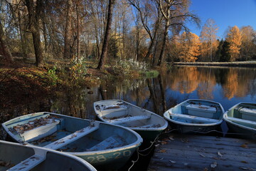 Moored boats with fallen leaves near the pier and shore in autumn