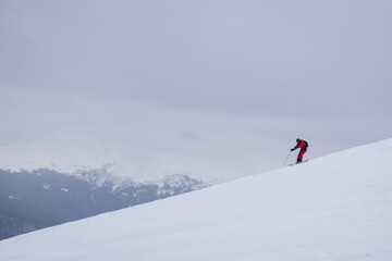 Fototapeta na wymiar The skier rides high in the snow in the mountains. Fog on the mountain and people skiing