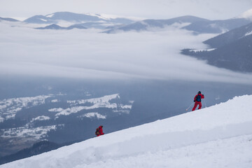 The skier rides high in the snow in the mountains. Fog on the mountain and people skiing