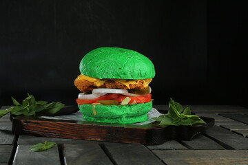 Green color Basil Burger chicken and beef served on a wooden pallet wooden black background