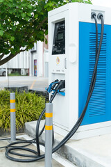 Electric car charging station for charge EV battery. Plug for vehicle with electric engine. EV charger. Clean energy. Charging point at car parking lot. Green power. Future transport technology.