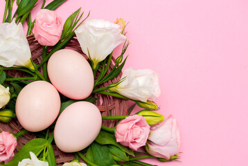 Fototapeta na wymiar Easter background with Easter eggs and spring flowers. Top view with copy space. Nest with eggs decorated with beautiful flowers on a pink background.