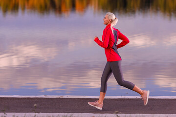 Fitness Runner Woman During Road Training for High Intensity Intervals and Sprint Workout Outdoors At Fall Near Scenic River  As Female Athlete Model Health Aspirations.