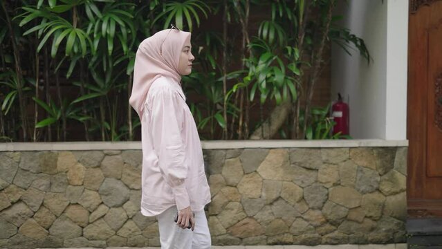 Modern Muslim Woman on Hijab Walking, Smiling, Looking her Smartphone