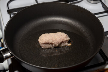 Fresh unfrozen turkey cutlets lie in oil in a frying pan