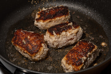 Turkey cutlets fried on one side lie in oil in a frying pan