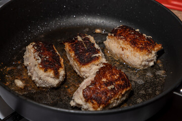 Turkey cutlets fried on one side lie in oil in a frying pan