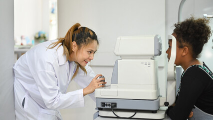 Teenage woman checking eyesight on auto refractor in ophthalmologist clinic. Eye health check and ophthalmology concept