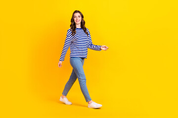 Fototapeta na wymiar Full size photo of attractive young woman walking going shopping promo wear trendy striped garment isolated on yellow color background
