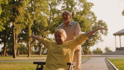 Excited aged couple having fun together in city park, life with disability