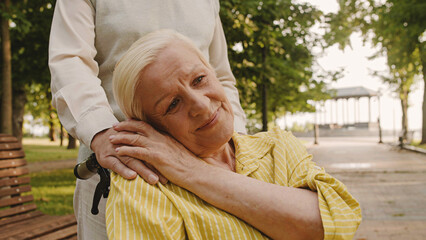 Grateful woman wheelchair user stroking husband's hand, family values, kindness