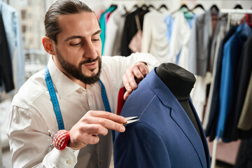 Clothier removing white stitches from client suit