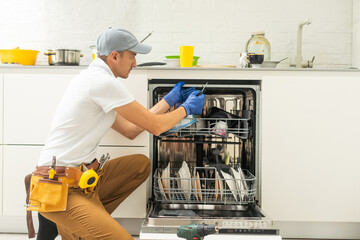 Repair of dishwashers. The master has come home and is repairing the dishwasher.