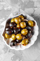 Delicious black and green olives in plate on gray background