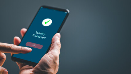 A businessman hand holds a smartphone on the screen with the message money sent transfer Concept. business, banking, financial online transactions with mobile devices. Copy space, Blurred background
