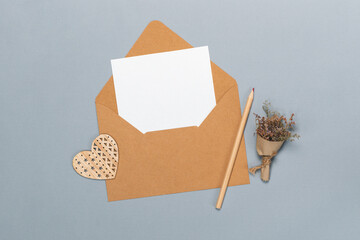 Above view St. Valentines day flat lay composition with craft paper envelope and blank white card...