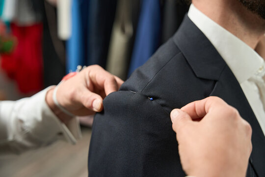 Professional tailor adjusting customer suit during fitting session