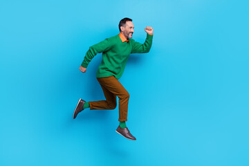 Fototapeta na wymiar Full body photo of mature handsome man running fast purposeful entrepreneur wear trendy green clothes isolated on blue color background